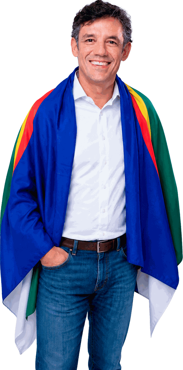 Daniel Coelho sorrindo, com a bandeira de Pernambuco sobre os ombros